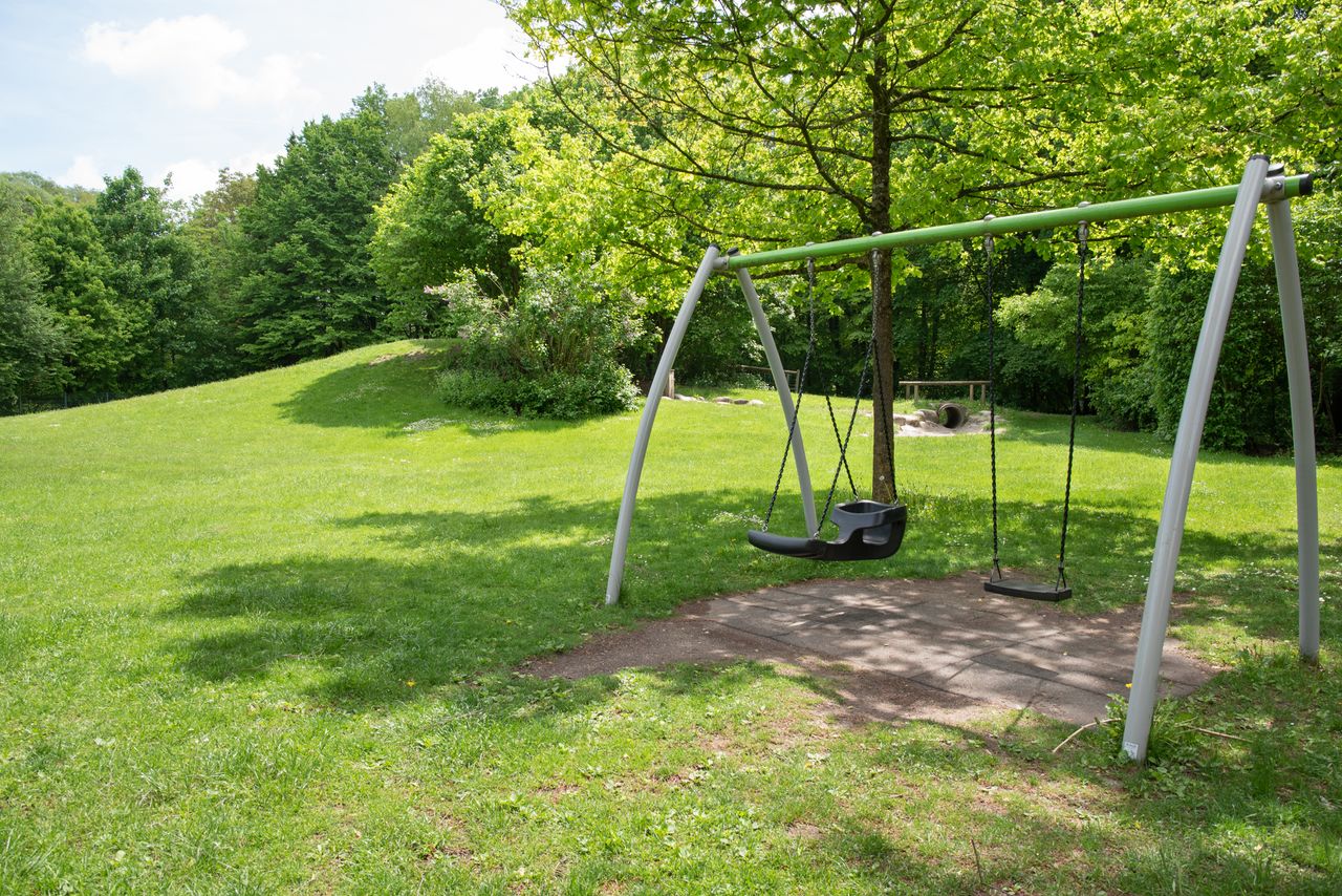 Schaukel und Schlittenberg im Hintergrund am Spielplatz Friedenstraße