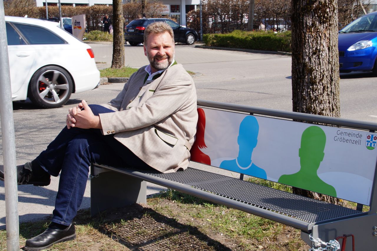 Bürgermeister der Gemeinde Gröbenzell Martin Schäfer testet eine Mitfahrbank