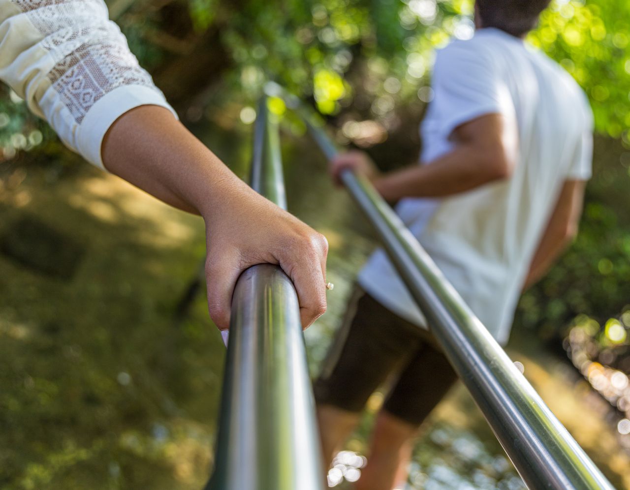 Personen kneippen im Gröbenbach und halten sich an der Stange in der Mitte fest