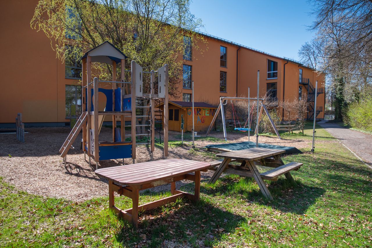 Spielgeräte und eine Sitzbänke im Garten der Ährenfeldschule/Ährenfeldfüchse