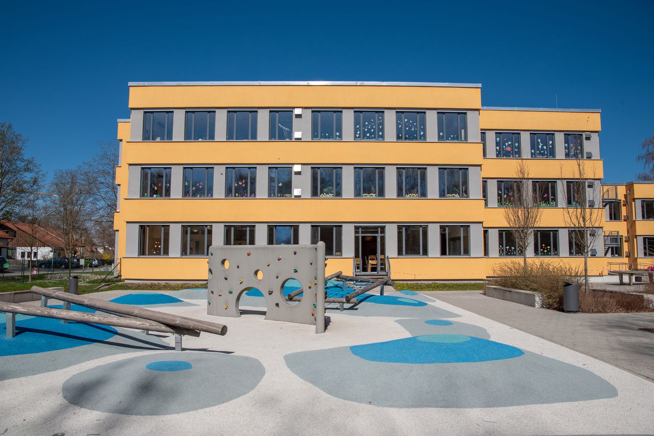 Spielgeräte und Pausenhof der Gröbenbachschule mit dem Schulgebäude im Hintergrund