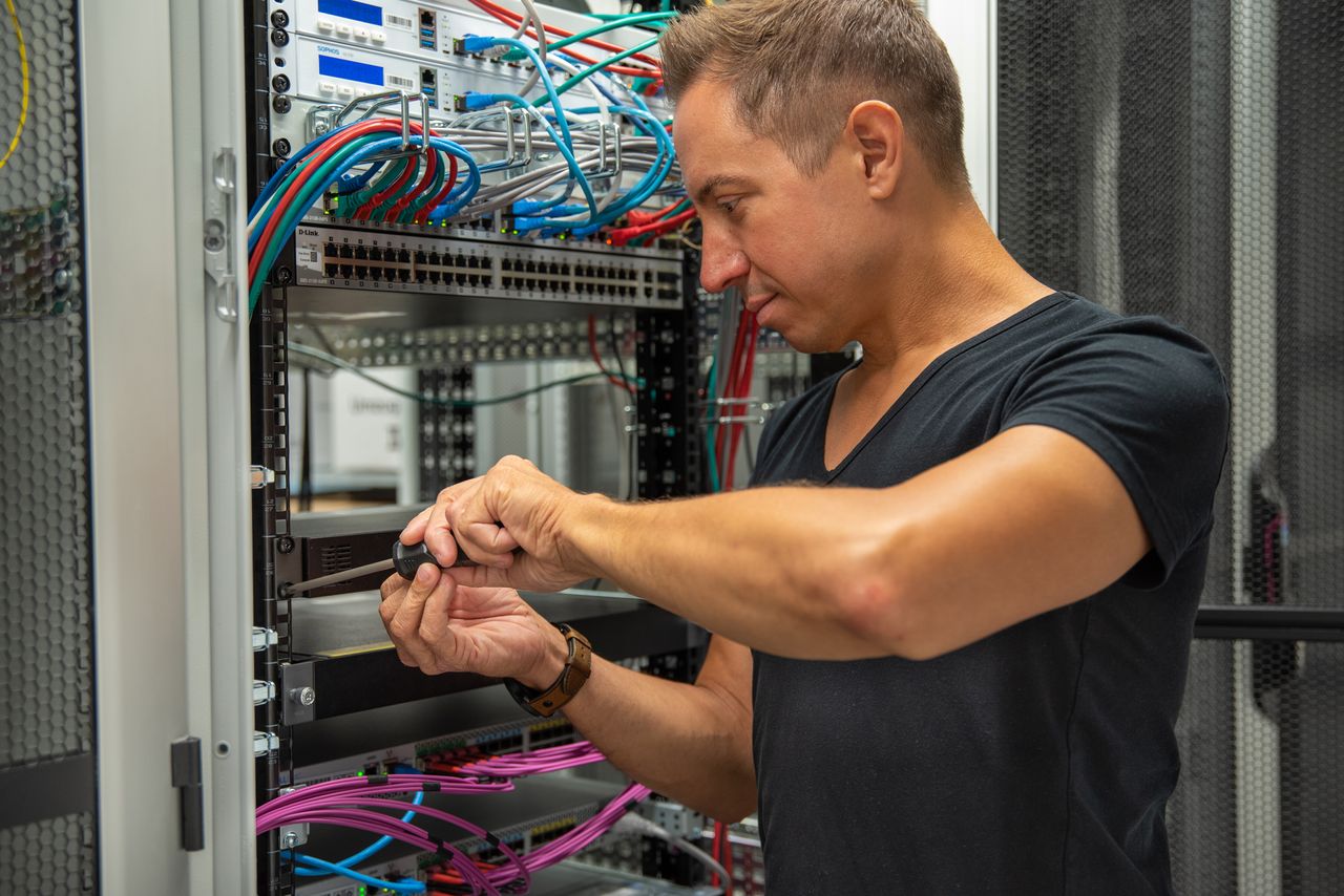 Ein Mitarbeiter der IT führt Wartungsarbeiten an einem Server-Rack durch