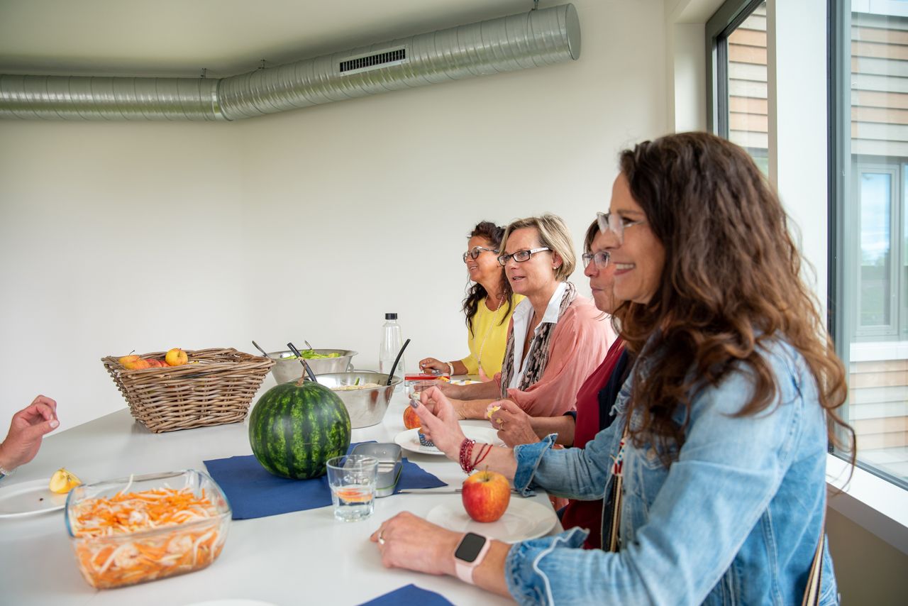 Mehrere Personen sitzen zur Mittagspause an einem großen Tisch in der großzügigen und hellen Küche des Rathauses