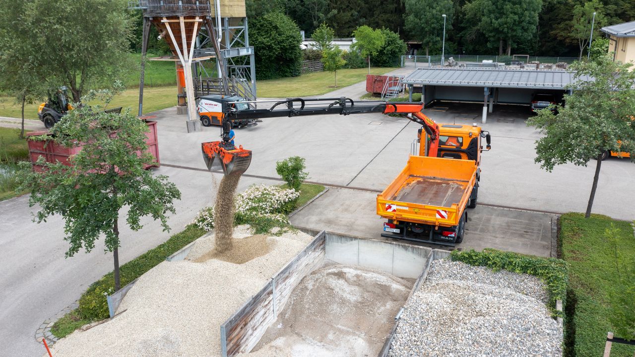 Kipper kippt Kies aus Schaufel auf Kieshaufen aus