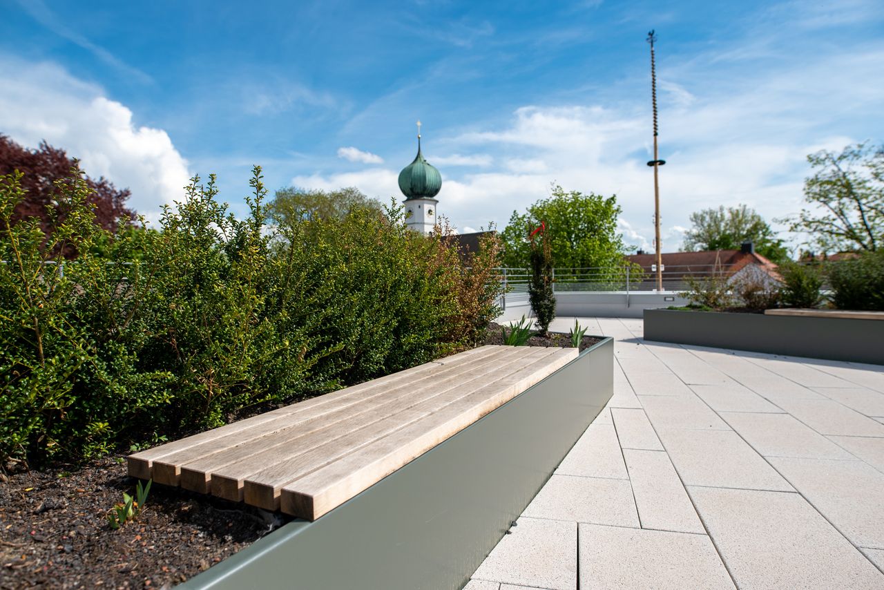 Dachterrasse des Gröbenzeller Rathauses mit bepflanzten Inseln und Sitzbänken rundherum