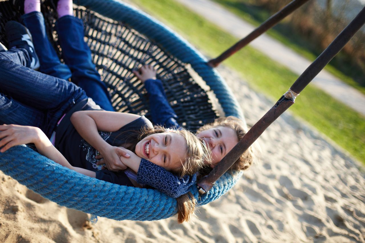 Zwei Mädchen auf Spielplatz in Nestschaukel