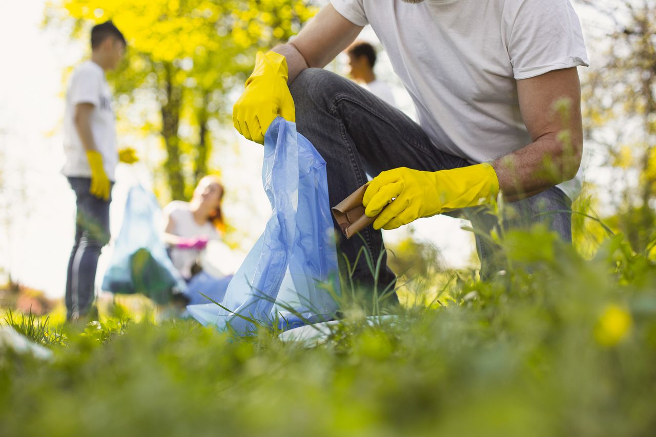 Mehrere Personen mit Müllsäcken beim Müllsammeln im Gras