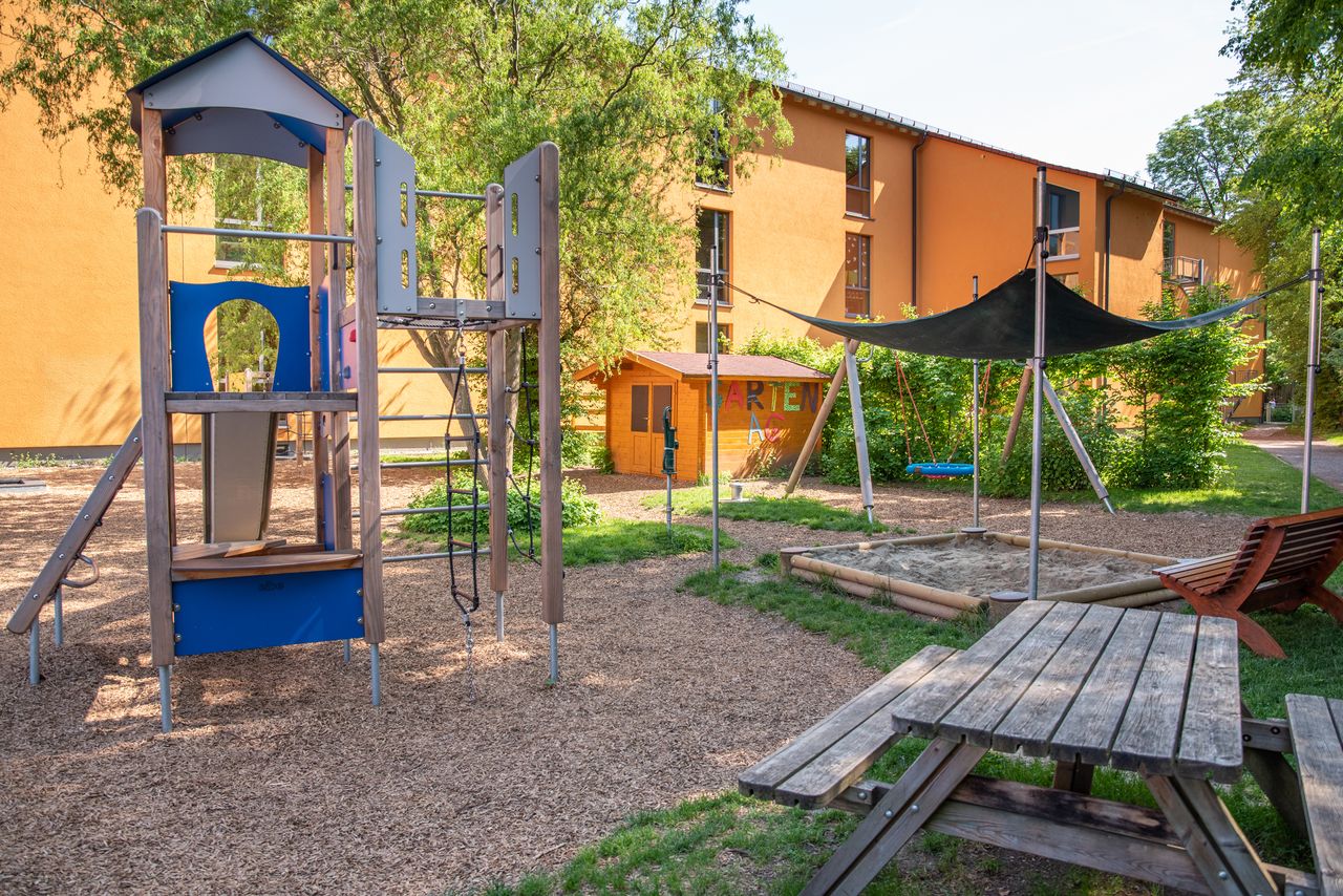 Garten des Kindergartens Ährenfeldfüchse mit einem Spielturm einem Gartenhaus, Sandkasten und Sitzbänken