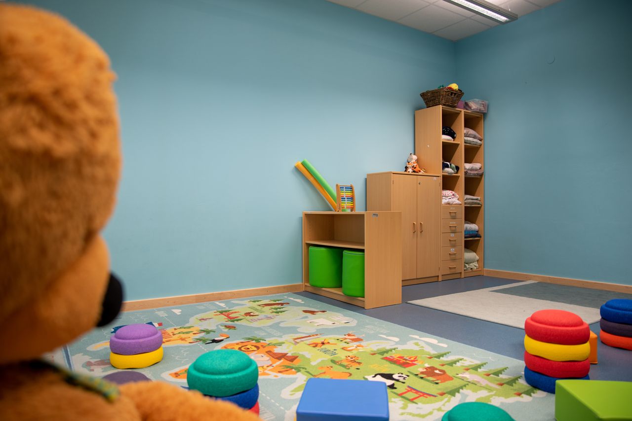 Ein Raum für Aktivitäten mit Spielsachen, Regalen und einem großen Teddybären im Vordergrund im Kindergarten Ährenfeldfüchse