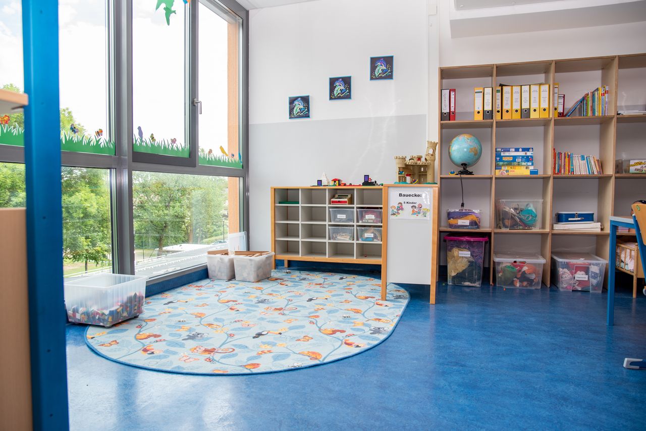 Eine Spielecke in der Mittagsbetreuung der Ährenfeldschule, am Boden ein Teppich, außen herum Regal mit verschiedenen Spielsachen