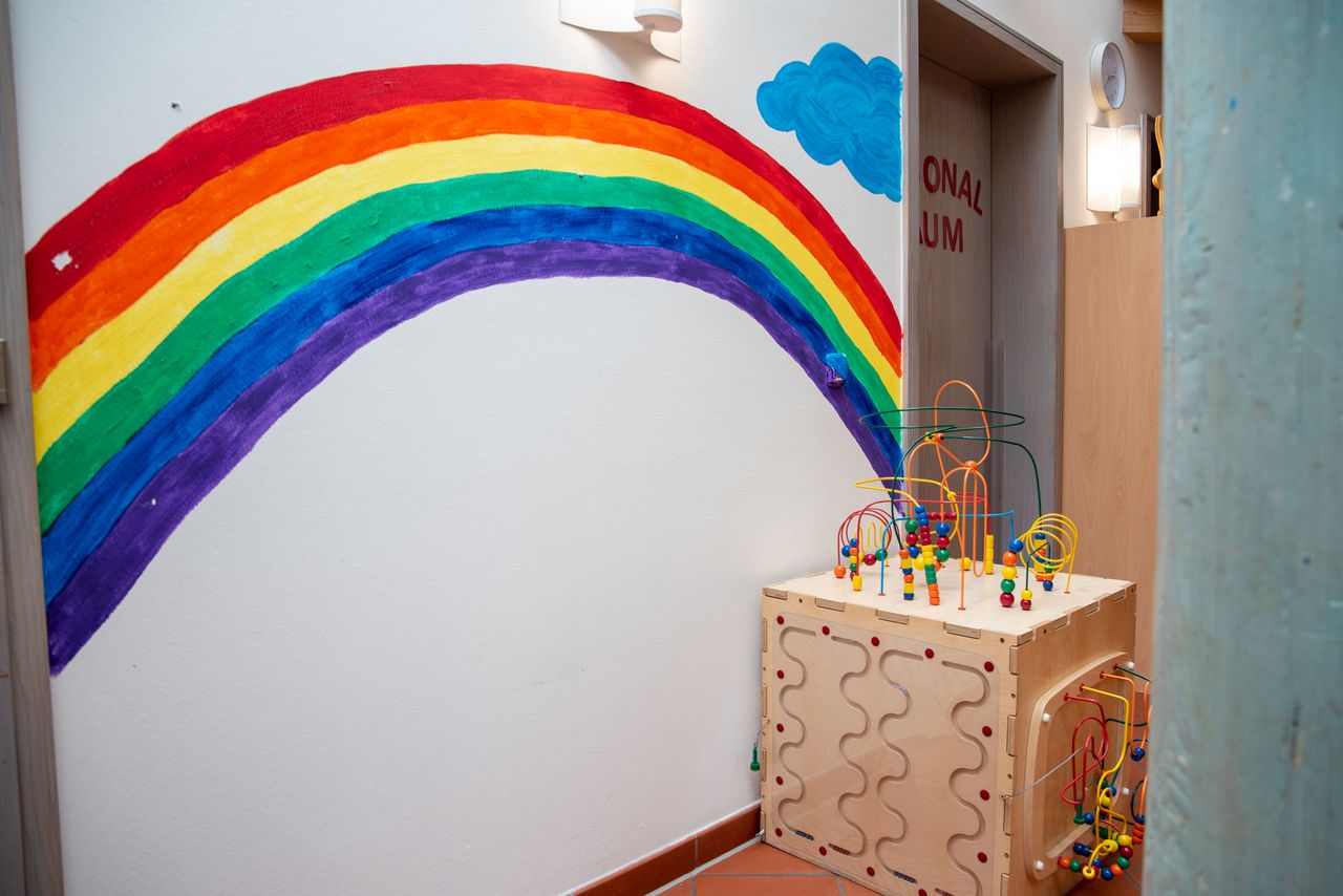 Regenbogen an einer weißen Wand, im Vordergrund Spielsachen