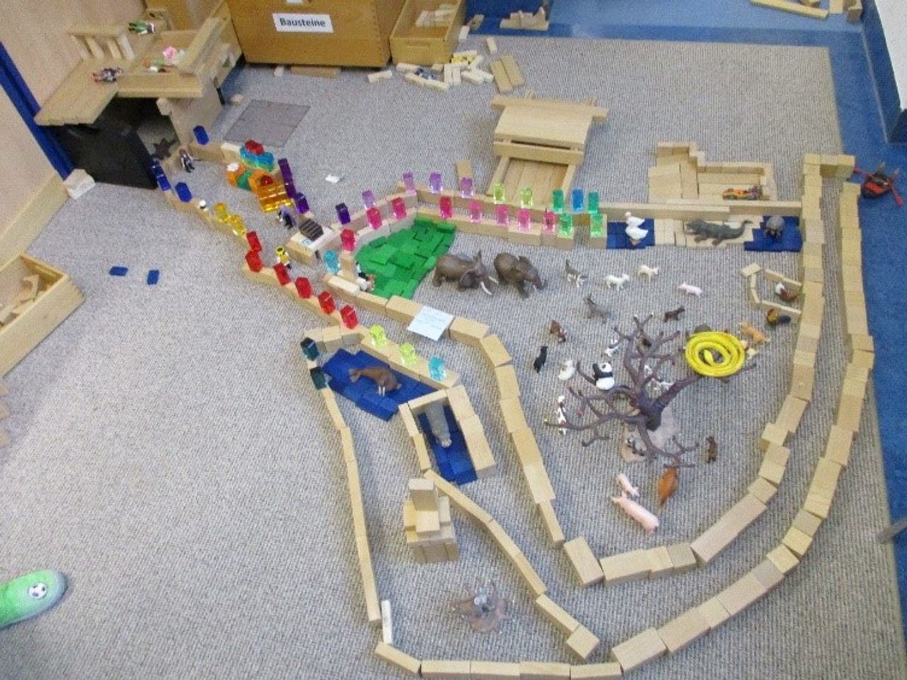 Zoo aus Bauklötzen und Tierfiguren, auf dem Teppich des Gruppenraums
