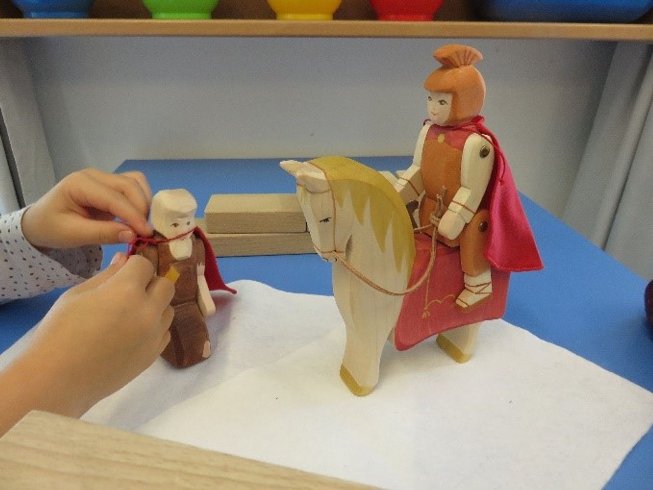 Kind spielt mit einem kleinen Holzpferd und einem Ritter.