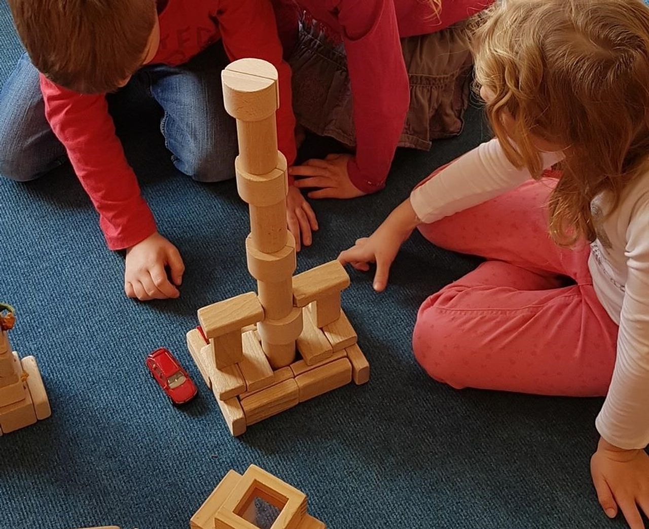 Zwei Kinder spielen mit Holzbausteinen.