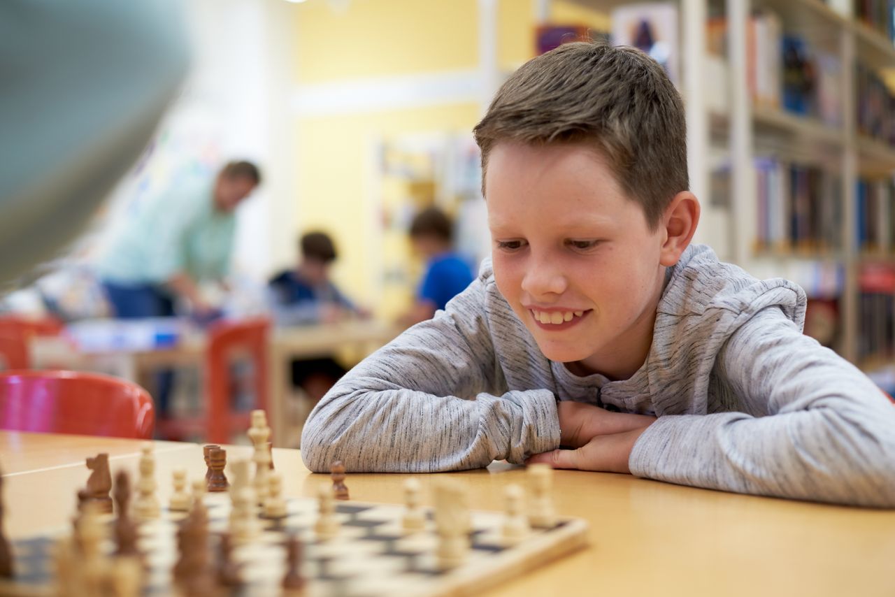 Spielen erwünscht!  Ein Junge spielt Schach in der Bücherei