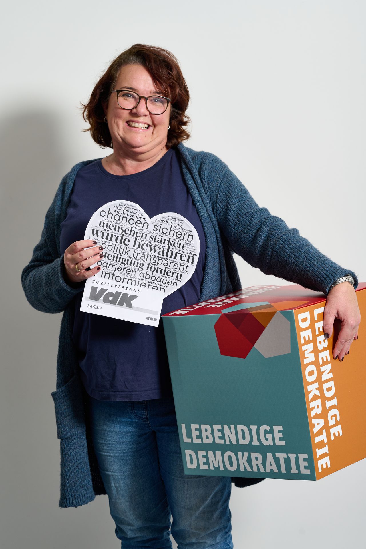 Frau hält einen Würfel mit "Lebendige Demokratie" und einem Herz vom VdK
