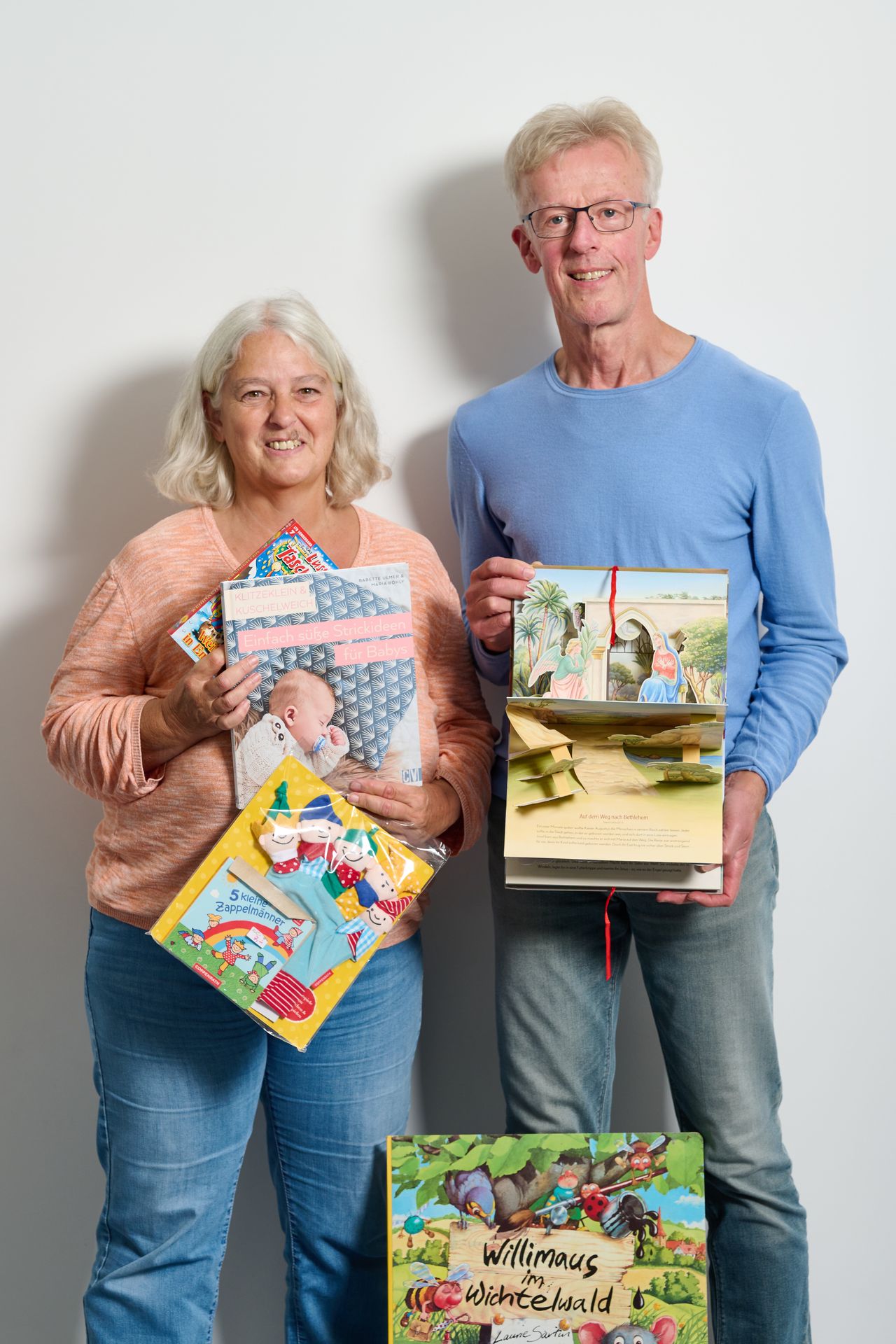 zwei Personen halten mehrere Bücher in der Hand.