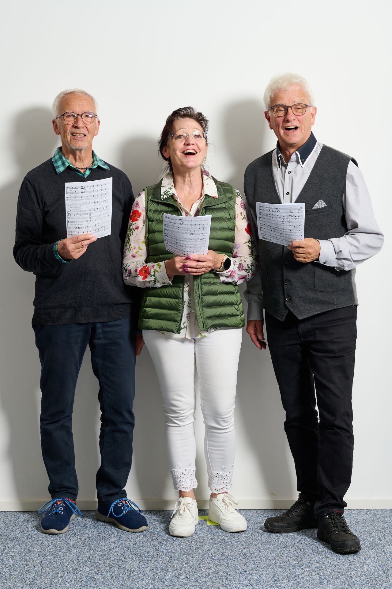 drei Leute singen und halten Notenblätter