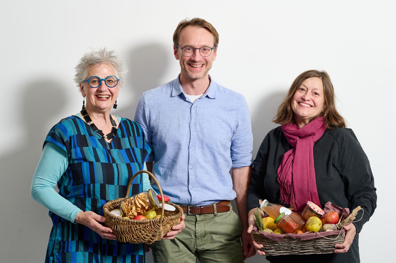 Drei Personen halten einen Korb voller Obst und Eingemachtem