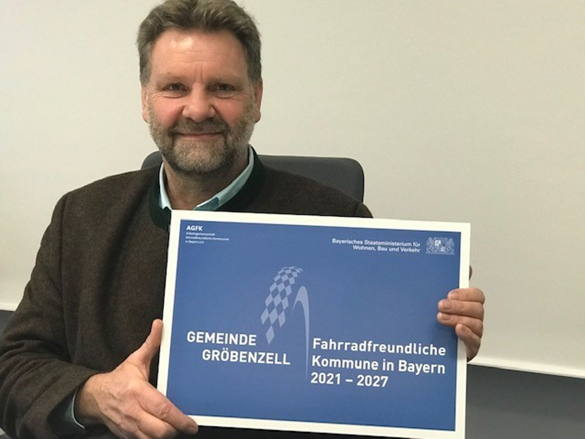 Auszeichnung: Gröbenzell ist nun „Fahrradfreundliche Kommune“ Martin Schäfer, Erster Bürgermeister der Gemeinde, hält die eingerahmte Auszeichnung sitzend in den Händen