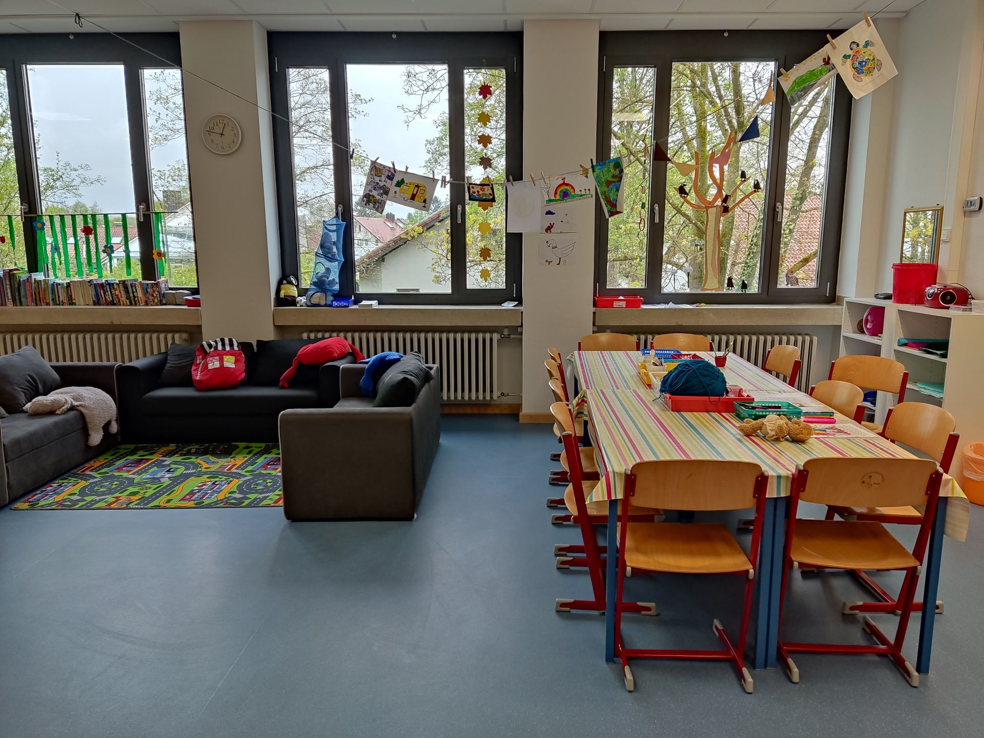 Gruppenraum mit Stühlen, Couchn, Tisch, bunten Bildern an den Wänden, etc.