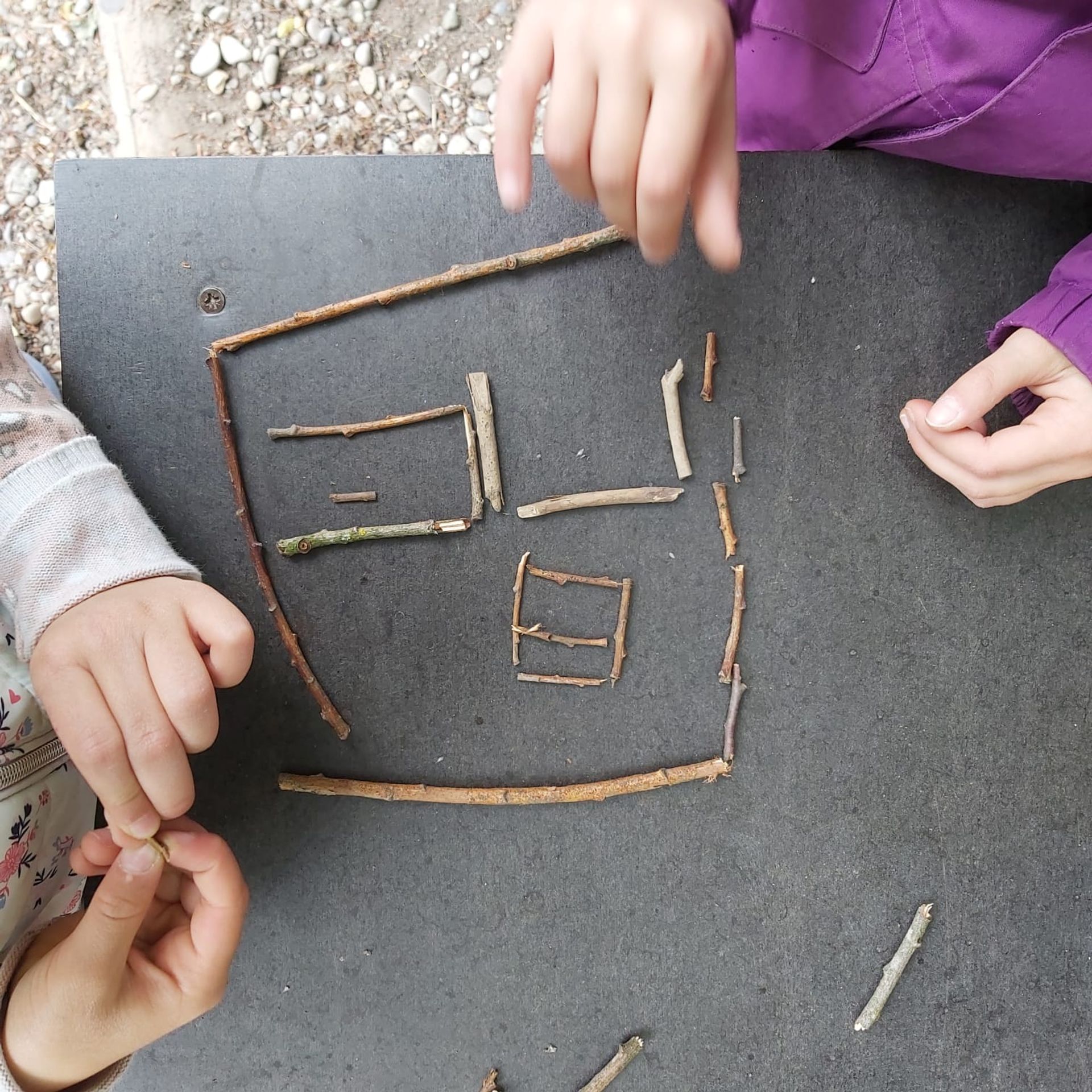 Kunst aus der Natur, mit der Natur Kinderhände legen aus Ästen ein Muster
