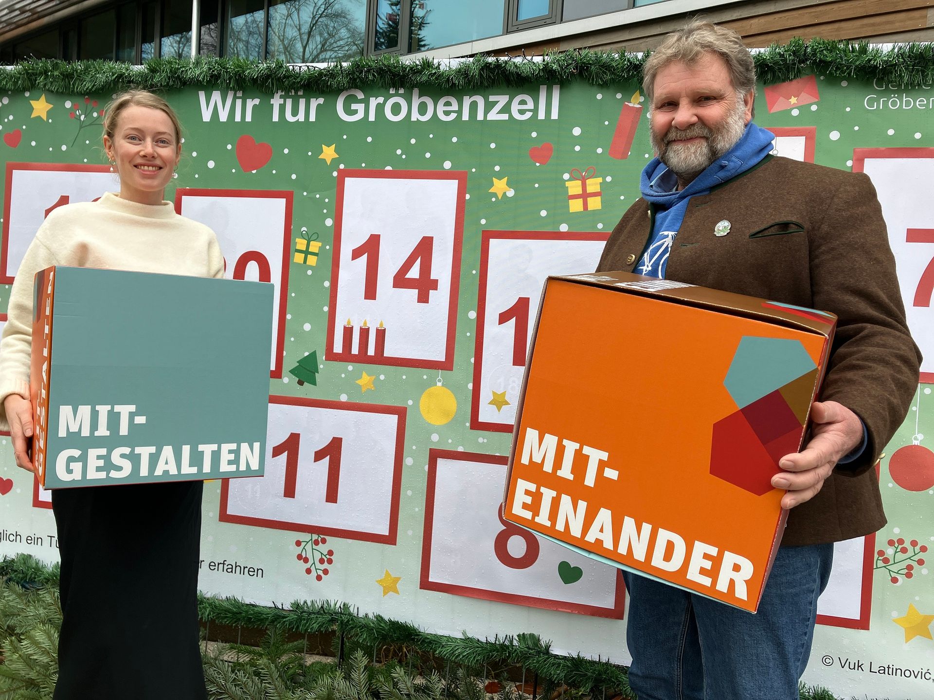 Ehrenamtskoordinatorin Lina Bischoff und Erster Bürgermeister Martin Schäfer vor dem Adventskalender.