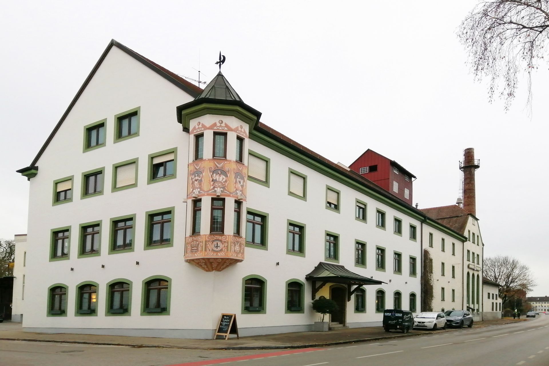 Foto des Maisacher Bräustüberls, davor verläuft die Straße, es parken Autos