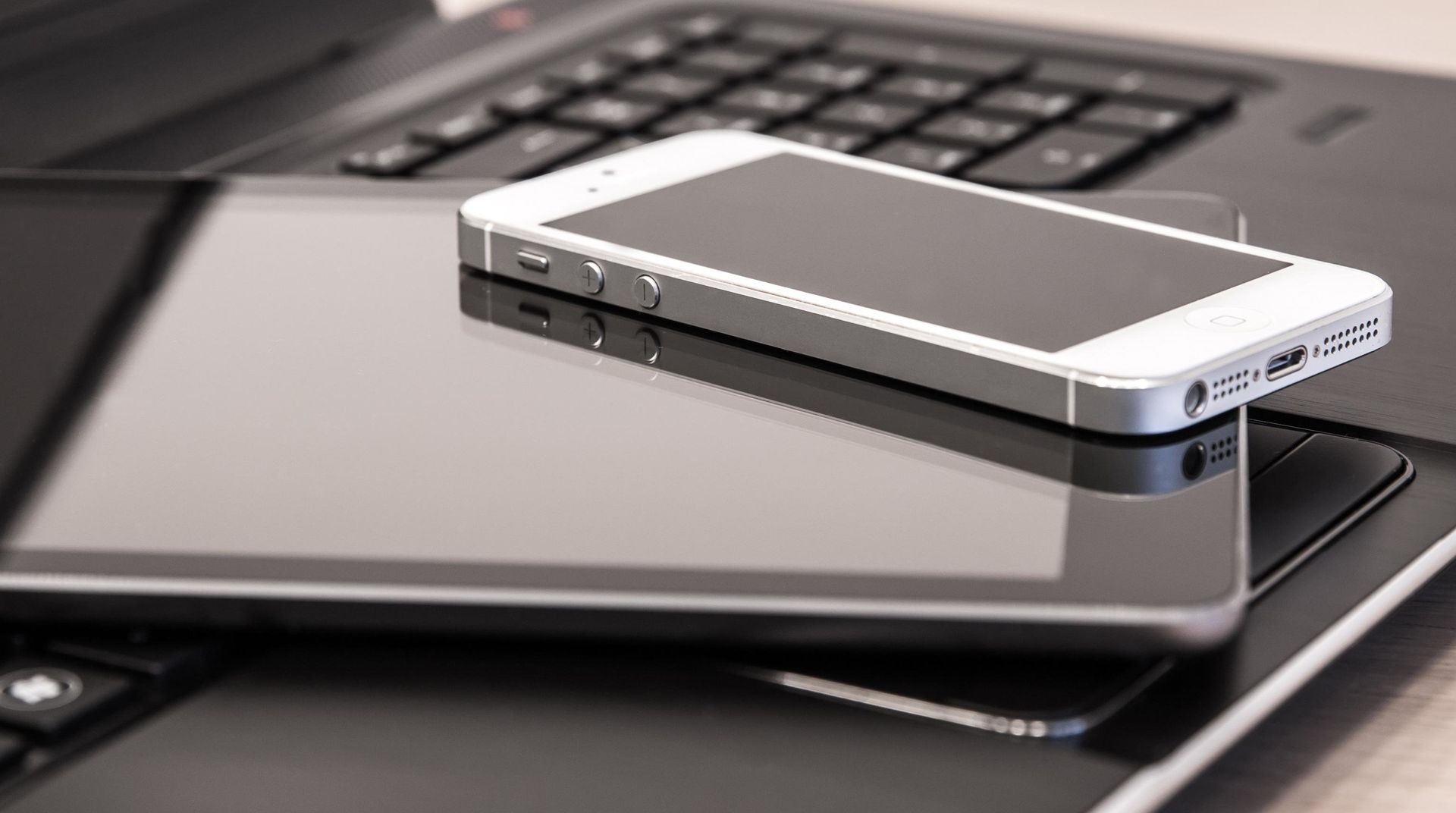 Auf einer Laptop-Tastatur liegt ein Tablet, darauf ein Smartphone