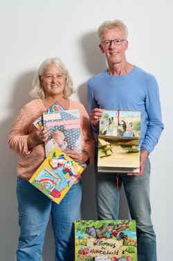 zwei Personen halten mehrere Bücher in der Hand.