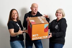 Drei Personen halten Würfel mit "Mitgestalten" in der Hand