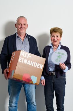 zwei Personen halten Würfel "Miteinander" und Frisbee mit dem Vereinslogo