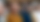 Frau im Auditorium lächelt freundlich beim aufmerksamen Zuhören, neben ihr sitzen (geblurred) weitere gut gelunte Menschen in mehreren Reihen und hören auch zu