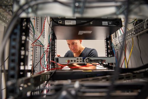  Ein Mitarbeiter der IT führt Wartungsarbeiten an einem Server-Rack durch