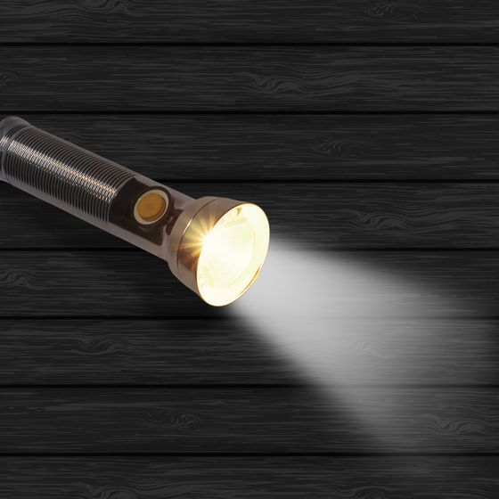 Taschenlampe liegt leuchtend auf schwarzem Hintergrund