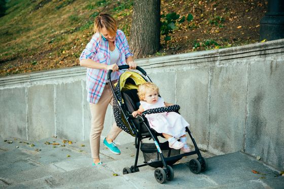 Frau schiebt Kinderwagen mit Baby