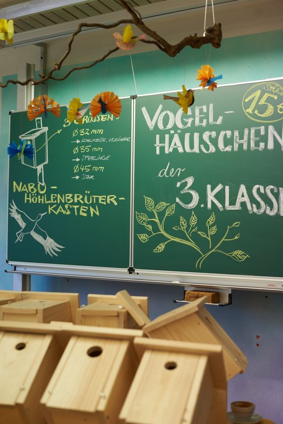 Herbstmarkt selbstgebaute Vogelhäuschen in einem Klassenzimmer vor einer Tafel.
