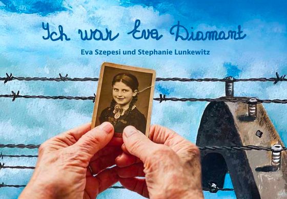 Zwei alte Hände halten ein vergilbtes Foto eines  jungen lächelnden Mädchens mit Zöpfen und Spitzenkragen. Dahinter sieht man einen Stacheldrahtzaun.