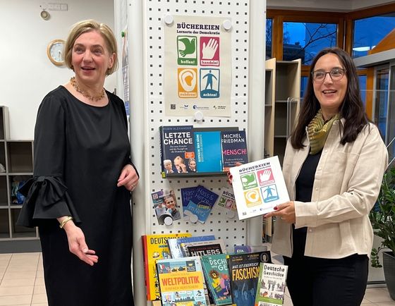 Sabine Adolph, Diözesanbibliothekarin der Erzdiözese München-Freising, überreicht Büchereileitung Kerstin Koppmann das Gütesiegel.