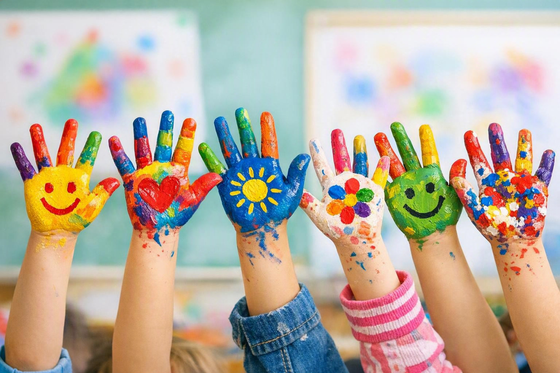 Kinderhände mit bunter Fingerfarbe bemalt.