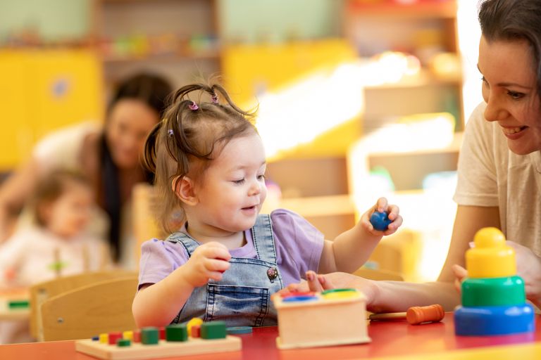 Erzieherin spielt mit kleinem Mädchen in Kinderkrippe