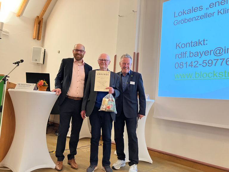 Prof. (emer.) Dr. Rudolf Bayer mit Erstem Bürgermeister Dr. Daniel Holmer (li.) und Walter Voit (re., Referent für Verkehr, Energie und Klimaschutz) auf der Bühne im Bürgerhaus Gröbenzell.